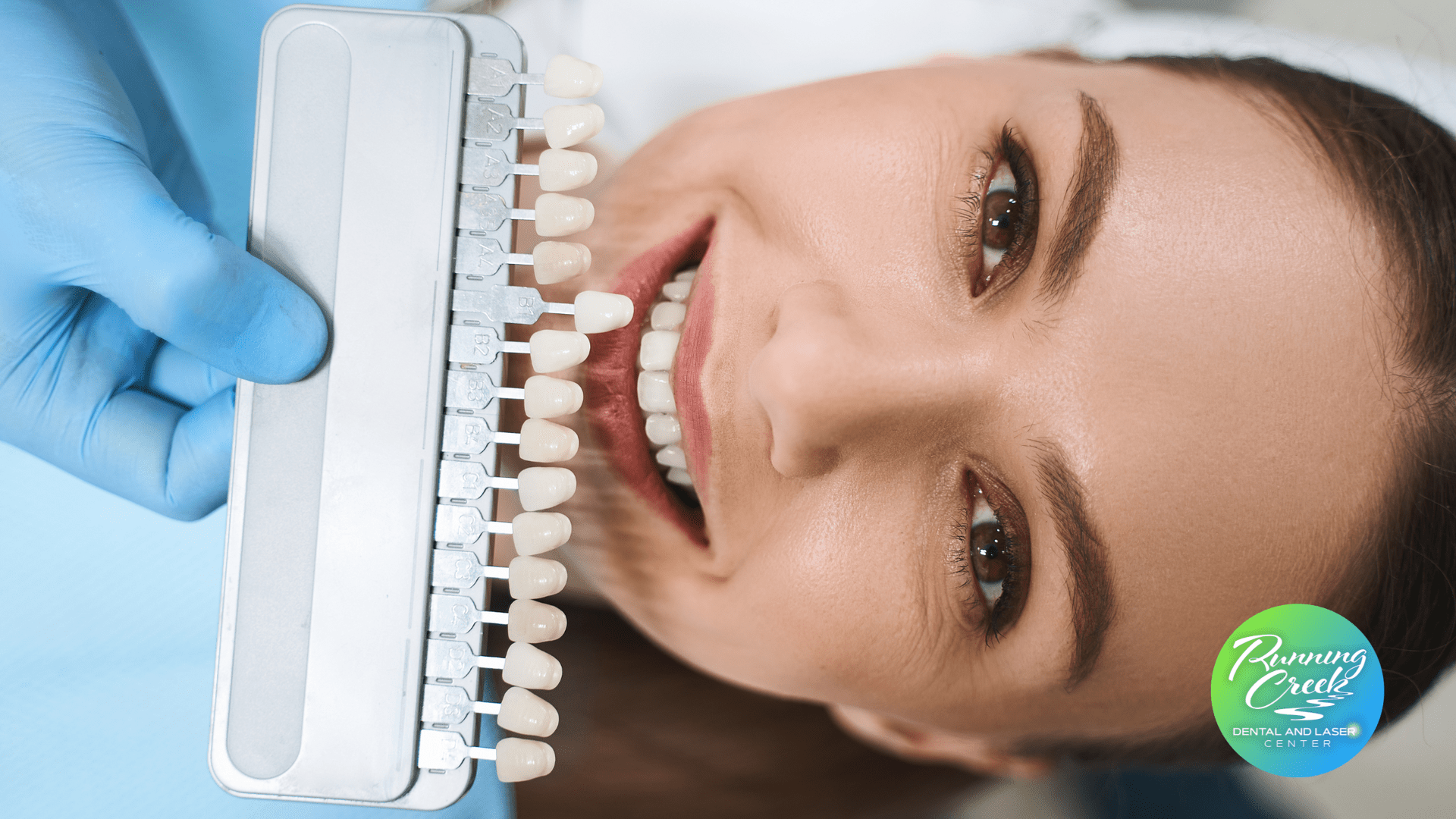 A woman is laying in a dental chair while a dentist examines her teeth.