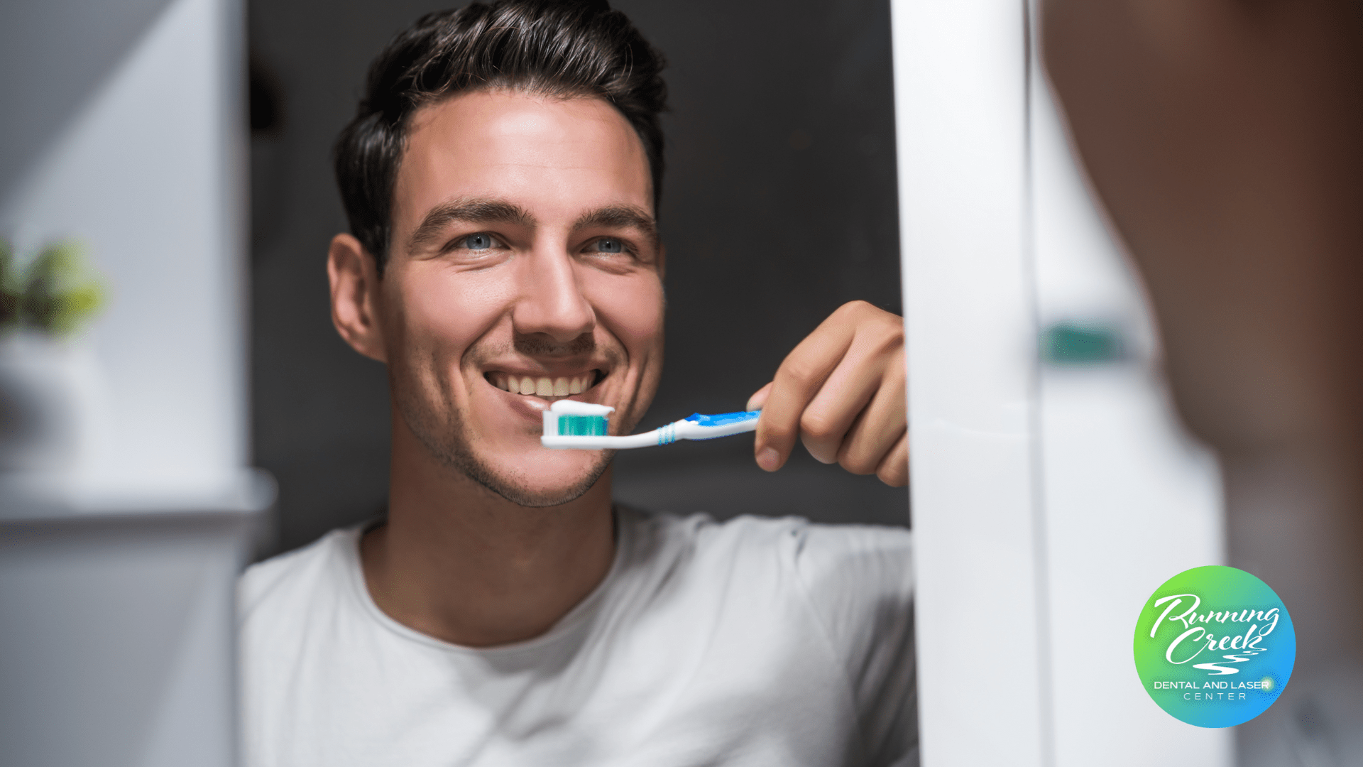 A man is brushing his teeth in front of a mirror.