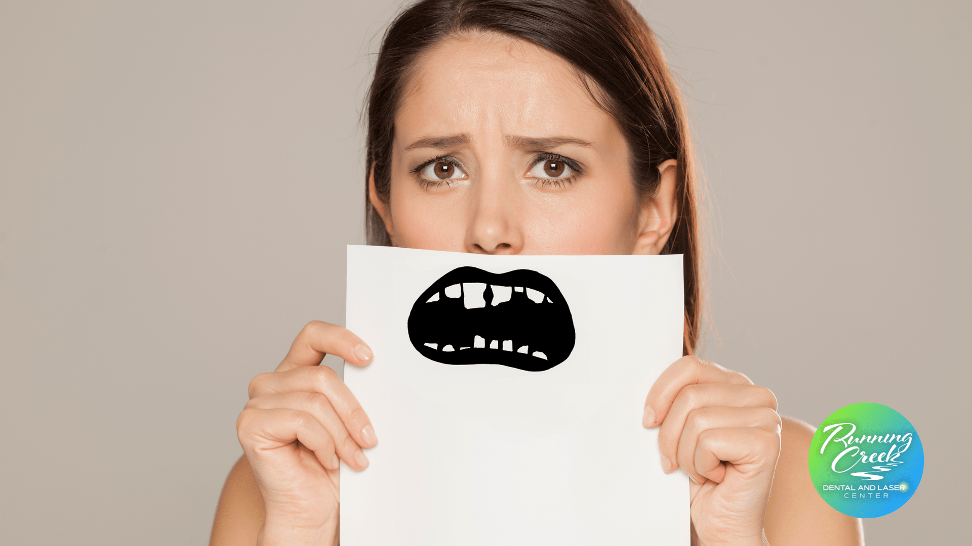 A woman is holding a piece of paper with a drawing of a mouth on it.