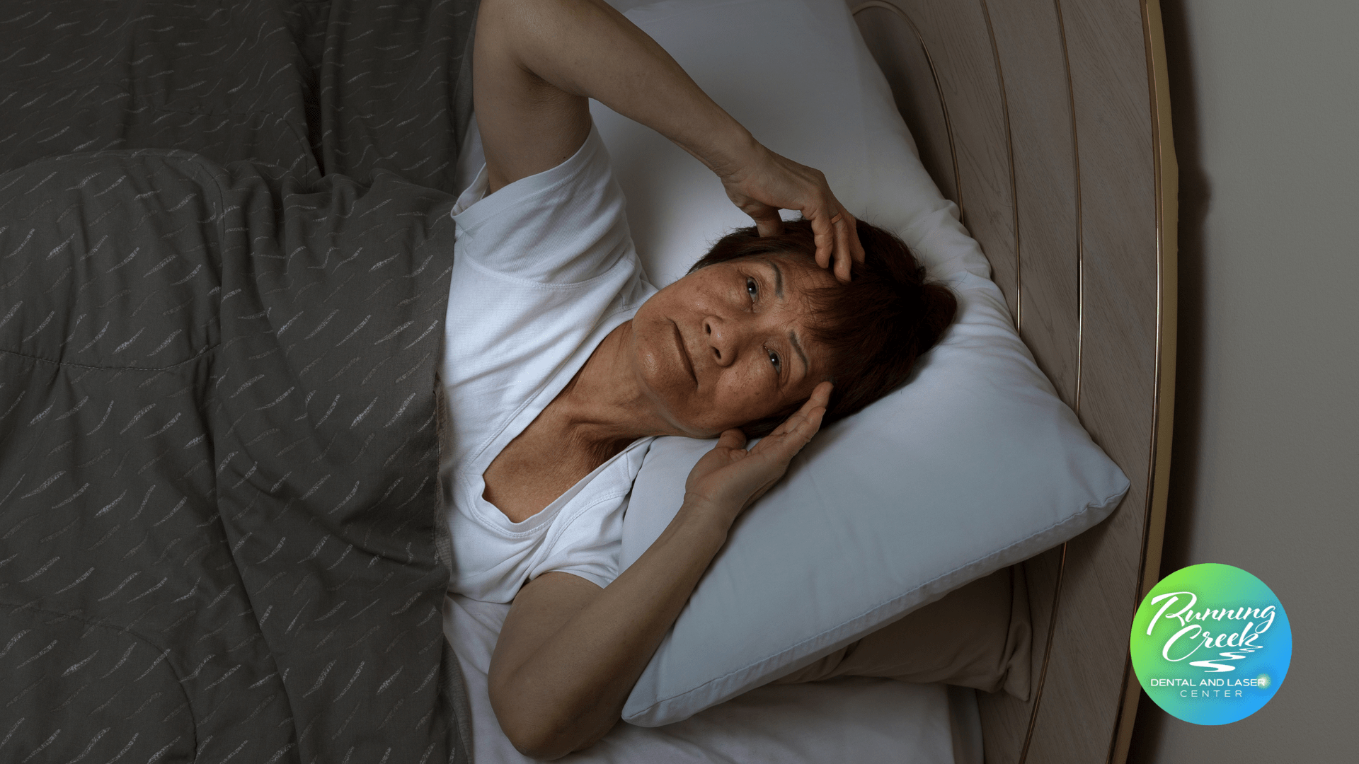 A woman is laying in bed with her head on a pillow.