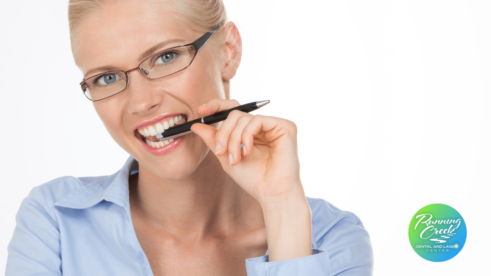 A woman wearing glasses is brushing her teeth with a pen