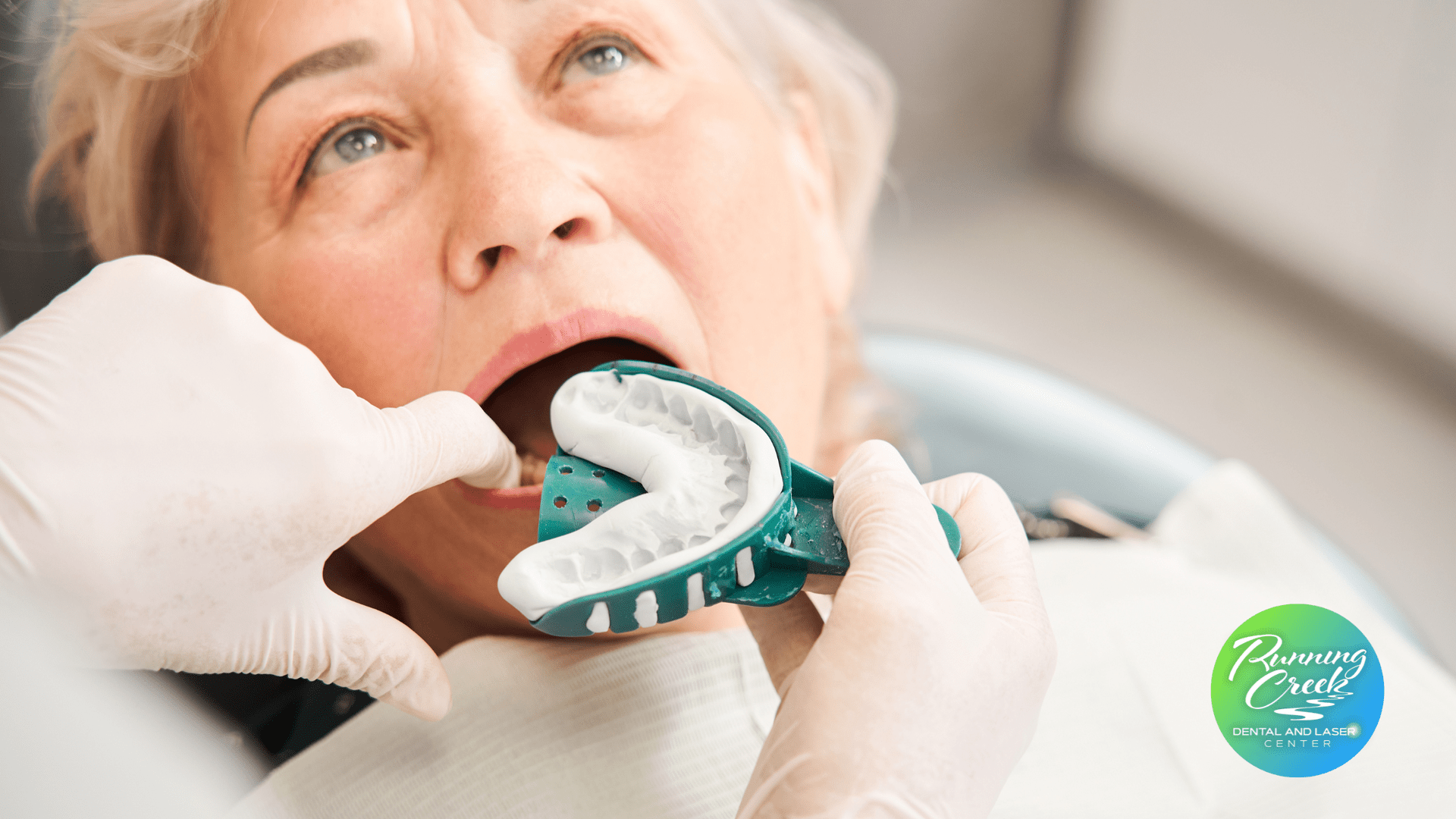 An elderly woman is getting her teeth examined by a dentist.