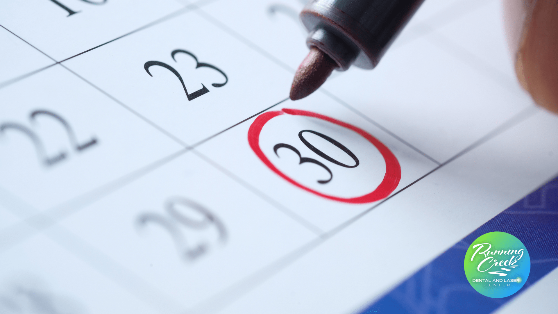 A person is drawing a red circle around the number 30 on a calendar
