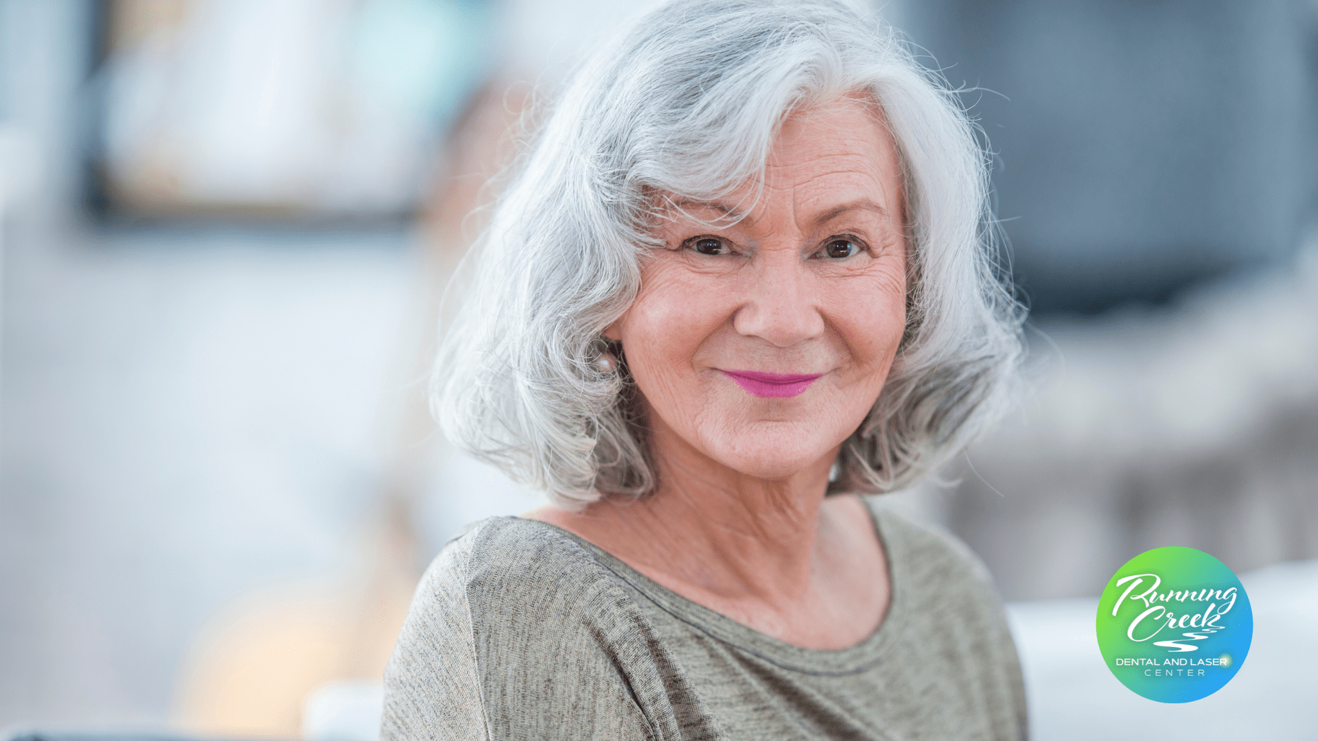 An elderly woman with gray hair is smiling for the camera.